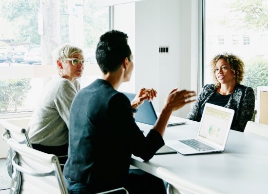 Three coworkers sitting at a conference table.